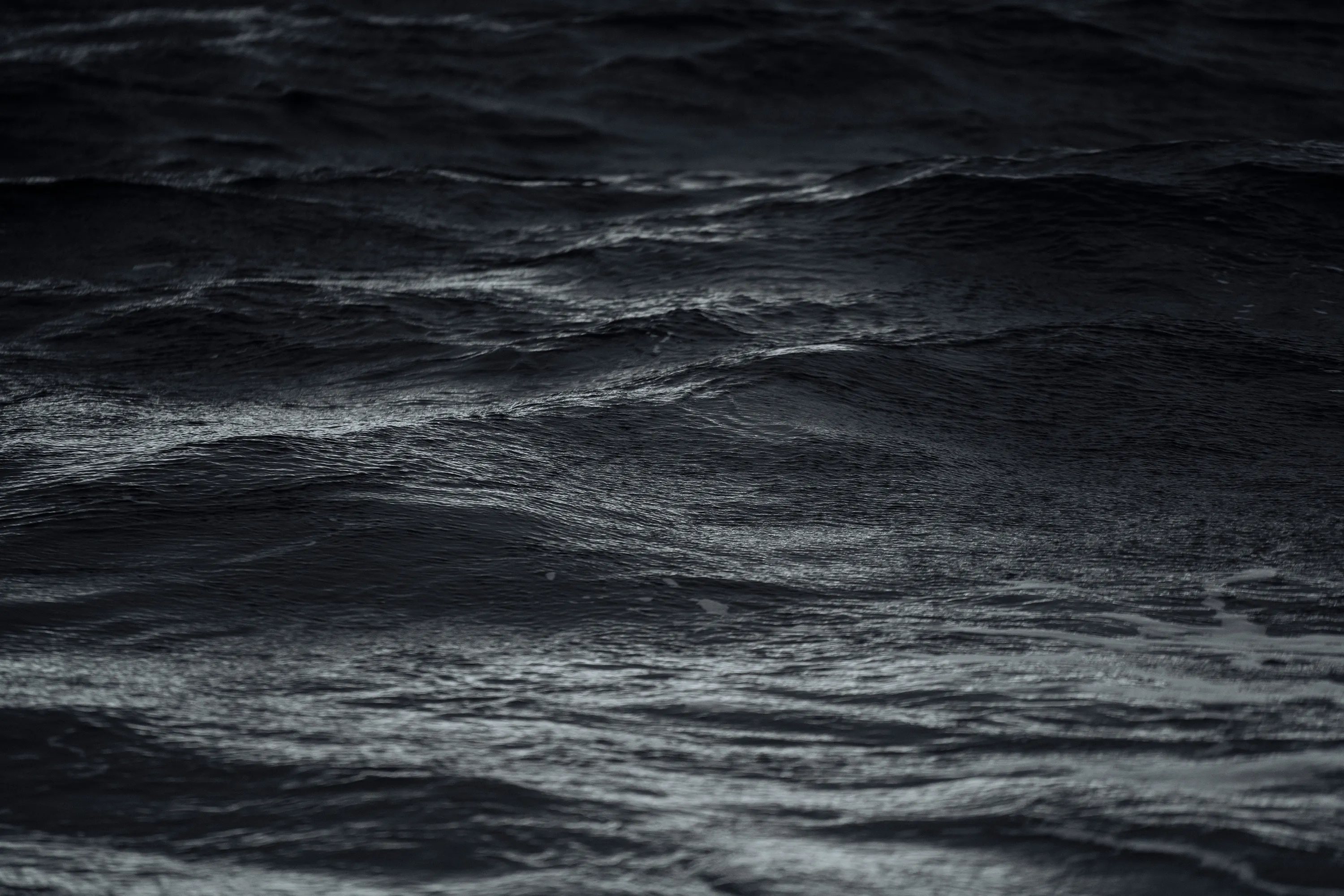 Waves disturb a dark body of water.